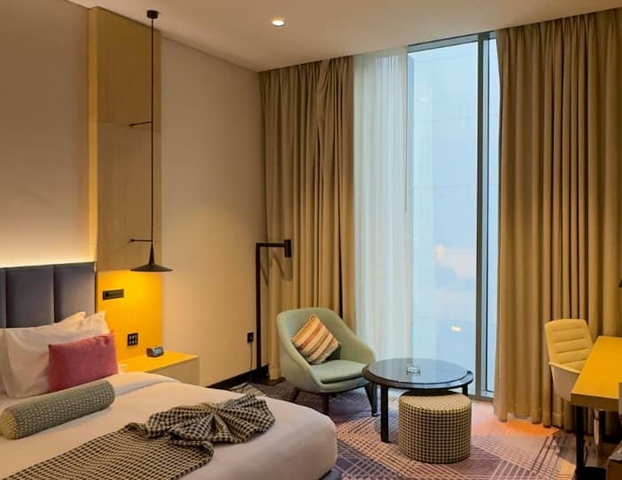 Interior of a modern, well-lit student apartment or hotel room with a desk and city view for students living in Australia.