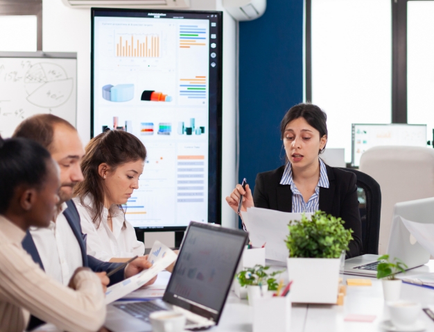A diverse business team collaborating and discussing data charts during a professional office meeting.