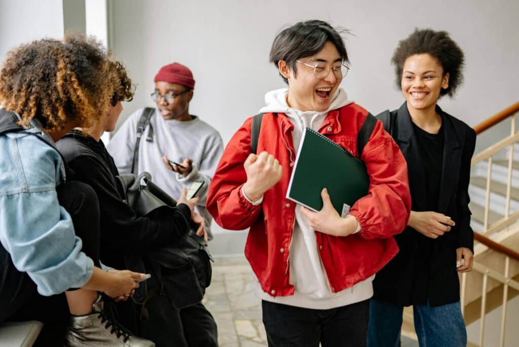 A diverse group of university students laughing and chatting together while standing on a campus staircase.
